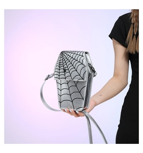 Detail of silver coffin-shaped crossbody bag featuring black spider web pattern and strap