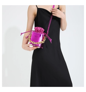 Dettaglio della mini borsa a tracolla fucsia metallizzata con catena dorata su abito nero