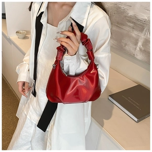 Glossy red PU leather crescent handbag with scrunchie handle held by a model