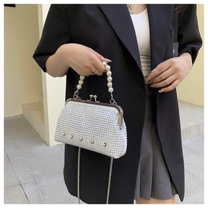 Close-up of white rhinestone evening bag with pearl handle and metal chain strap