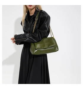 Olive green PU leather shoulder bag with gold chain strap shown on black outfit