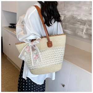 Detail of woven straw bag with pink rose embroidery and delicate lace ribbon