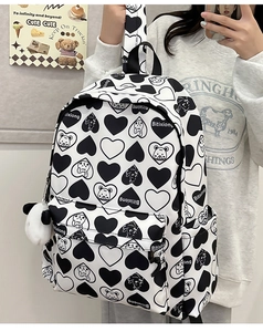 Detail shot of a black and white nylon backpack with cartoon bear patterns and panda charm