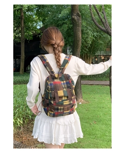 Close-up of vintage plaid wool backpack with leather buckle detail in outdoor setting