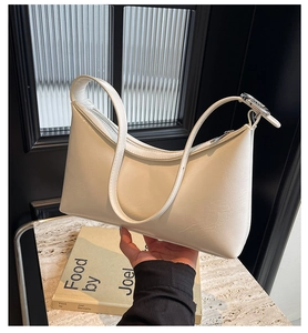 Macro view of the cream white PU leather texture and metallic zipper of the shoulder bag