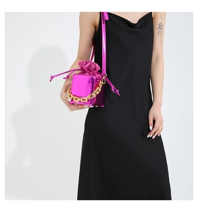 Dettaglio borsa a cubo fucsia brillante con catena dorata e chiusura a coulisse in pelle