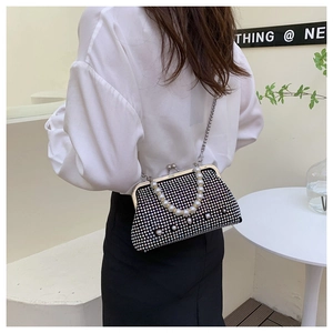 Detail of black rhinestone evening bag with pearl accents and delicate metal chain strap