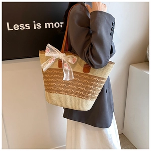Detail view of woven straw tote bag with lace bow and pink floral embroidery accents