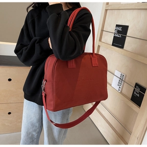 Close-up of vintage red canvas tote bag with embossed text and long shoulder strap