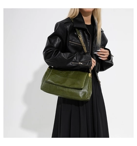Detail view of dark green PU leather handbag with chunky gold chain strap on model