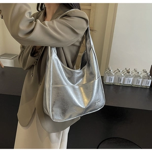 Detail of silver metallic tote bag featuring textured leather and a wide shoulder strap