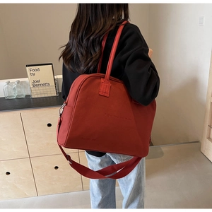 Detail of burgundy canvas tote bag with adjustable wide strap shown in a lifestyle setting