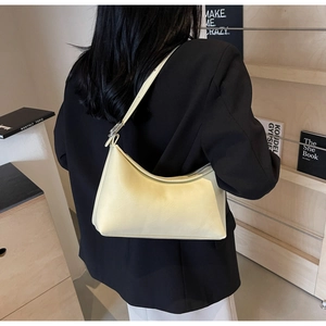 Detail of pale yellow hobo shoulder bag in textured PU leather with silver buckle strap
