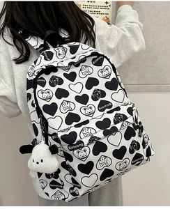 Detail of white nylon backpack with bear and heart prints shown on model back