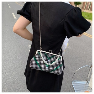 Close-up of a sparkling rhinestone evening bag with green V-pattern and pearl handle