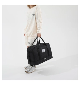 Detail of black travel bag with shoe compartment, handles, and adjustable shoulder strap