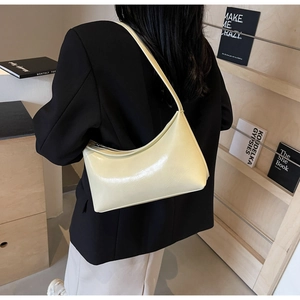 Detail of trendy light yellow glossy PU leather hobo bag worn over the shoulder