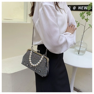Detail of black rhinestone evening bag featuring pearl handle and metallic chain strap