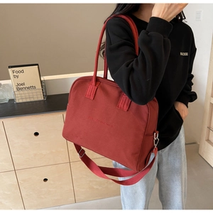 Close-up of red canvas handbag with Enjoy Life and Travel embossed text and strap