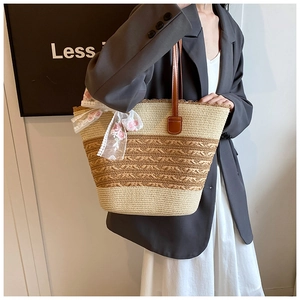 Detail of hand-woven straw tote bag featuring a lace bow with pink floral embroidery