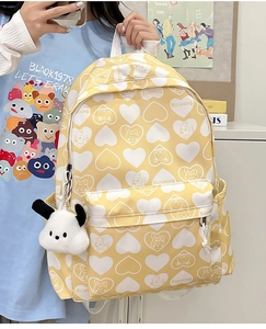 Detail of yellow nylon backpack featuring cartoon bear print and white puppy plush keychain