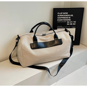 Large beige canvas travel tote bag with black leather straps and adjustable shoulder strap