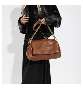 Close-up of caramel brown PU leather shoulder bag with vintage texture and gold chain