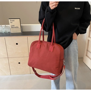 Detail of dark red canvas tote bag with Enjoy Life embossed text and sturdy dual handles