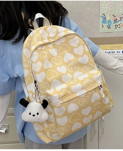 Detail view of yellow nylon backpack with heart prints and plush dog charm