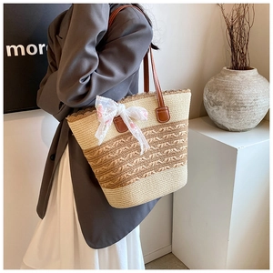 Detail showing two-tone straw weaving pattern with a brown leather strap and lace bow