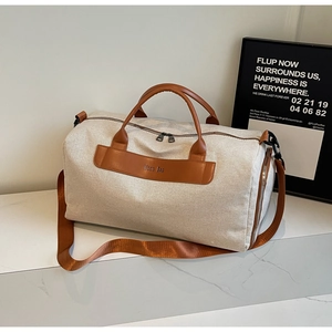 Minimalist beige canvas duffle bag with brown leather handles and adjustable shoulder strap