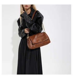 Detail of vintage brown oil-wax PU leather shoulder bag with gold chain strap on model