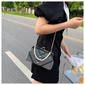 Detail of evening bag featuring green rhinestones, heart charm, and pearl handle strap