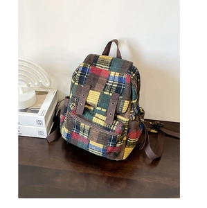 Rainbow tweed patchwork backpack with brown canvas straps on a rustic wooden desk