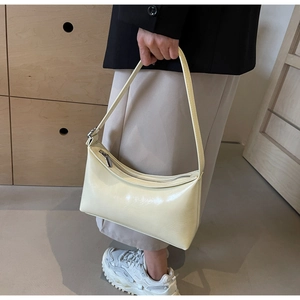 Chic cream PU leather shoulder bag with glossy finish worn by model in a minimalist room