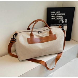 Minimalist canvas tote bag with brown leather trim and shoulder strap on white display