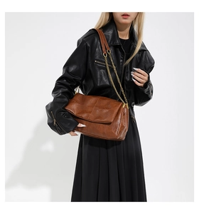 Detail of vintage brown PU leather handbag featuring a gold metal chain and leather strap