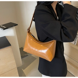 Detail of caramel glossy PU leather underarm bag with adjustable shoulder strap