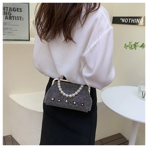 Detailed view of black rhinestone clutch with elegant large imitation pearl handle strap