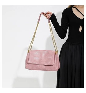 Detailed close-up of a pink quilted PU leather handbag with golden chain strap on a model