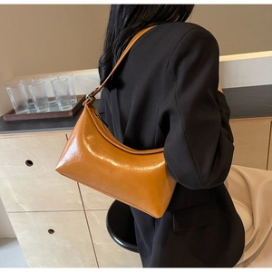 Close-up of a mustard yellow faux leather hobo bag styled with a black blazer