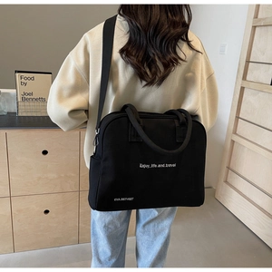 Detail of a black canvas tote bag with Enjoy life and travel print shown in a lifestyle shot