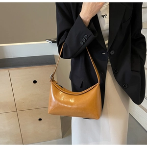 Detail of yellow glossy PU leather hobo bag with adjustable silver buckle on a model