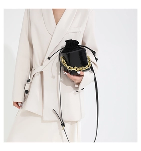 Dettaglio mini borsa a scatola in pelle verniciata nera con catena d'oro e coulisse