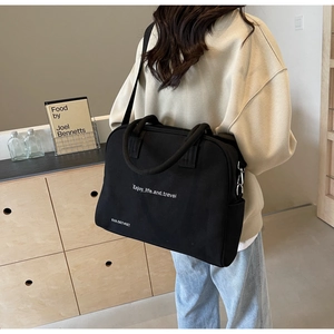 Detail view of black canvas tote bag with white text print and metal strap hooks