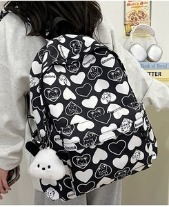 Detail of nylon backpack with heart pattern, cartoon bear print, and plush charm pendant
