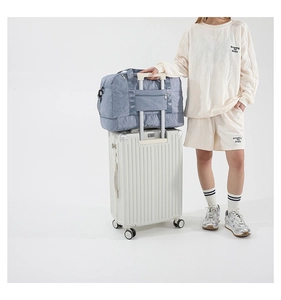 Blue travel bag detail showing star-stitched pattern and suitcase trolley sleeve