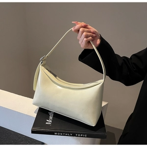 Detailed view of cream-colored crescent bag with silver buckles and smooth PU leather texture