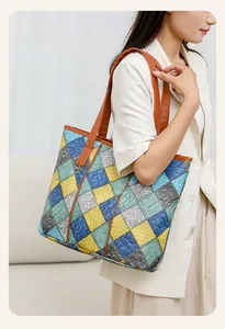 Detail of multi-color patchwork tote bag with crocodile texture on model in beige suit