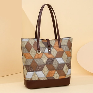 Close-up of geometric patchwork tote bag with brown and silver embossed leather textures